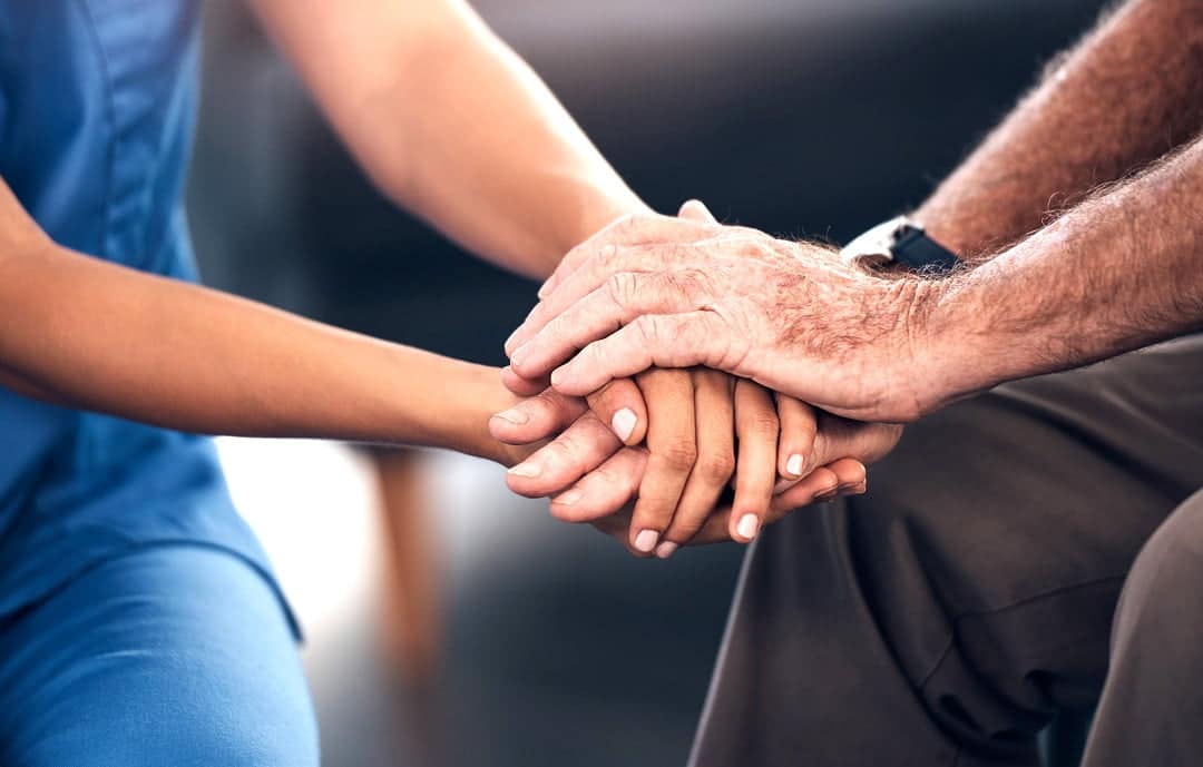 Photo: Cropped shot of a senior man and a nurse holding hands